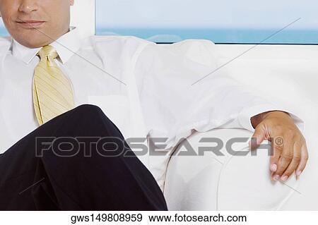 Close-up of a businessman sitting on a couch View Large Photo Image Stock Photo - Close-up of a businessman sitting on a couch. Fotosearch