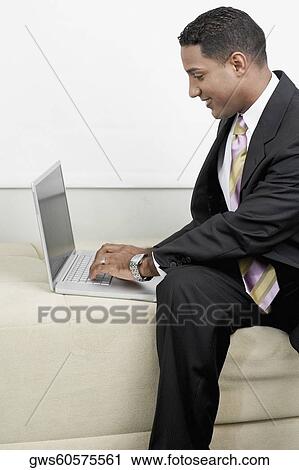 Close-up of a businessman using a laptop on a couch View Large Photo Image Stock Image - Close-up of a businessman using a laptop on a couch. Fotosearch
