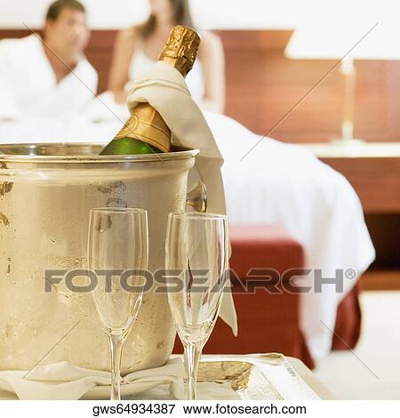 Stock Photo - Close-up of a champagne bottle in an ice bucket with two champagne flutes. Fotosearch