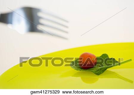 Close-up of a cherry tomato with a spinach leaf on a plate View Large Photo Image Stock Photo - Close-up of a cherry tomato with a spinach leaf on a plate. Fotosearch