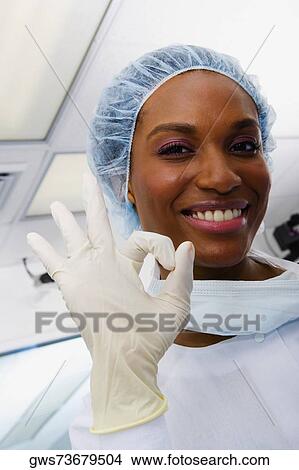 Picture - Close-up of a female surgeon smiling and making an OK sign. Fotosearch
