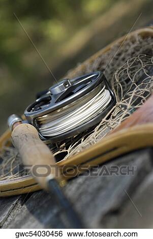 Stock Photograph - Close-up of a fishing rod with a fishing reel and a net. Fotosearch