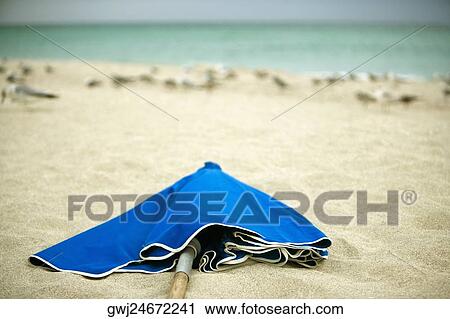 Close-up of a folded beach umbrella on the beach View Large Photo Image Stock Image - Close-up of a folded beach umbrella on the beach. Fotosearch