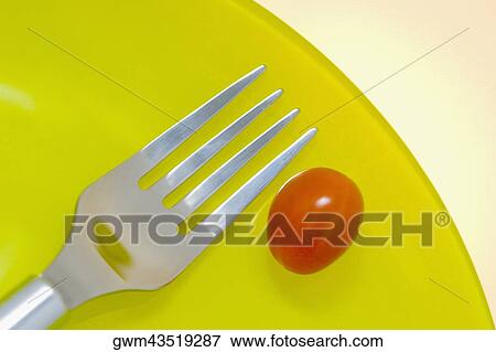 Stock Photo - Close-up of a fork with a cherry tomato on a plate. Fotosearch