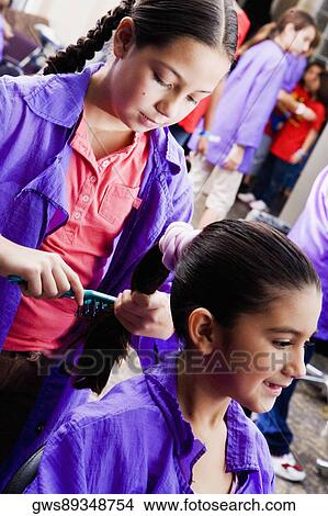Close-up of a girl combing her sister's hair in a salon View Large Photo Image Picture - Close-up of a girl combing her sister's hair in a salon. Fotosearch