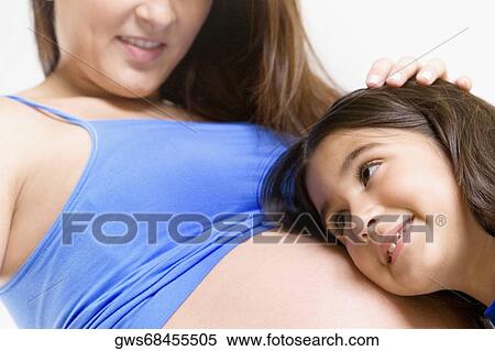 Close-up of a girl listening to a pregnant young woman's abdomen and smiling View Large Photo Image Stock Photography - Close-up of a girl listening to a pregnant young woman's abdomen and smiling. Fotosearch