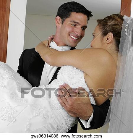 Close-up of a groom carrying his bride and looking at each other View Large Photo Image Stock Photograph - Close-up of a groom carrying his bride and looking at each other. Fotosearch