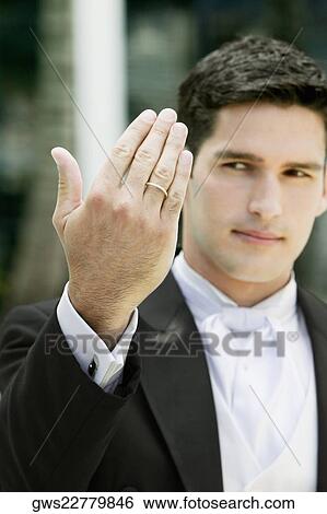 Stock Photograph - Close-up of a groom showing his wedding ring. Fotosearch