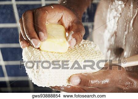 Picture - Close-up of a human hand applying soap on a back brush. Fotosearch