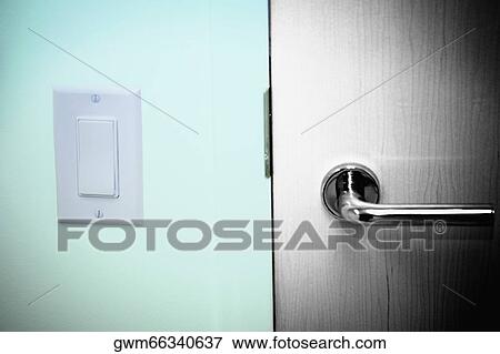 Stock Photo - Close-up of a light switch near a door handle. Fotosearch