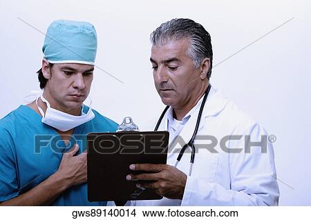Close-up of a male doctor discussing a report with a surgeon View Large Photo Image Picture - Close-up of a male doctor discussing a report with a surgeon. Fotosearch