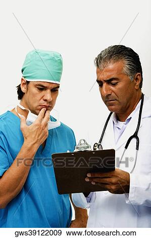 Close-up of a male doctor discussing a report with a surgeon View Large Photo Image Stock Photo - Close-up of a male doctor discussing a report with a surgeon. Fotosearch