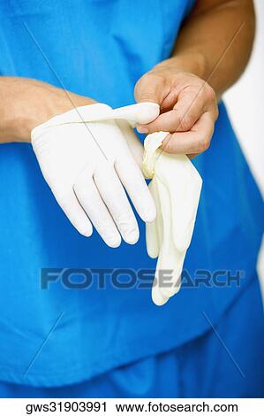 Stock Image - Close-up of a male surgeon's hand removing a surgical glove from his hand. Fotosearch