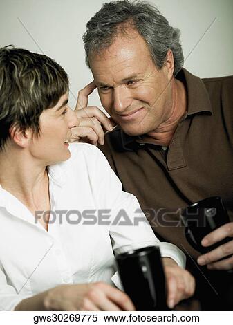 Stock Photography - Close-up of a mature couple holding cups of tea and looking at each other. Fotosearch