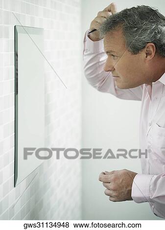 Close-up of a mature man combing his hair in front of a mirror View Large Photo Image Stock Photo - Close-up of a mature man combing his hair in front of a mirror. Fotosearch