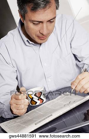 Close-up of a mature man holding a cup of coffee and doing a crossword puzzle View Large Photo Image Stock Image - Close-up of a mature man holding a cup of coffee and doing a crossword puzzle. Fotosearch