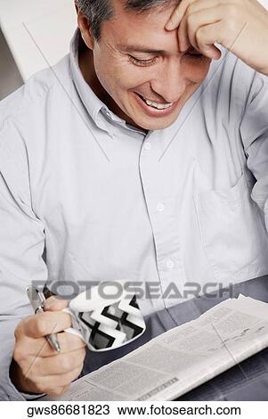 Close-up of a mature man holding a cup of coffee and reading a newspaper View Large Photo Image Stock Image - Close-up of a mature man holding a cup of coffee and reading a newspaper. Fotosearch