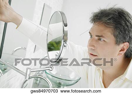 Stock Image - Close-up of a mature man looking at a mirror. Fotosearch
