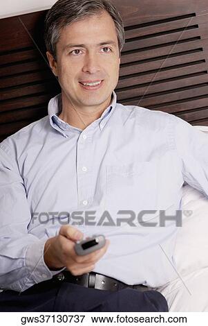 Close-up of a mature man operating a remote control and smiling on the bed View Large Photo Image Stock Photo - Close-up of a mature man operating a remote control and smiling on the bed. Fotosearch