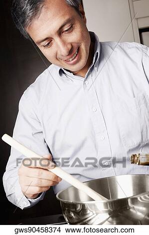Close-up of a mature man preparing food in the kitchen and smiling View Large Photo Image Picture - Close-up of a mature man preparing food in the kitchen and smiling. Fotosearch