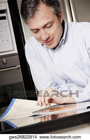 Close-up of a mature man reading a spiral notebook and smiling View Large Photo Image Picture - Close-up of a mature man reading a spiral notebook and smiling. Fotosearch