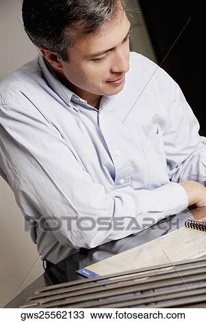 Stock Image - Close-up of a mature man reading a spiral notebook. Fotosearch