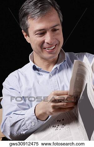 Stock Photography - Close-up of a mature man reading a newspaper and smiling. Fotosearch