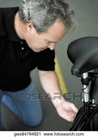 Stock Image - Close-up of a mature man repairing his bicycle. Fotosearch