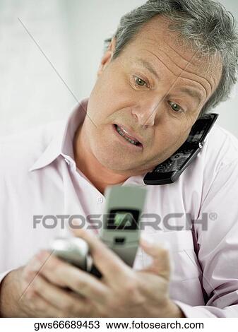 Close-up of a mature man talking on a mobile phone and holding two mobile phones in his other hand View Large Photo Image Stock Image - Close-up of a mature man talking on a mobile phone and holding two mobile phones in his other hand. Fotosearch