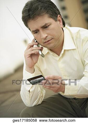 Close-up of a mature man talking on a mobile phone and holding a credit card View Large Photo Image Stock Photo - Close-up of a mature man talking on a mobile phone and holding a credit card. Fotosearch