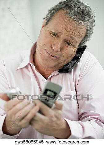 Close-up of a mature man talking on a mobile phone and holding two mobile phones in his other hand View Large Photo Image Stock Photography - Close-up of a mature man talking on a mobile phone and holding two mobile phones in his other hand. Fotosearch