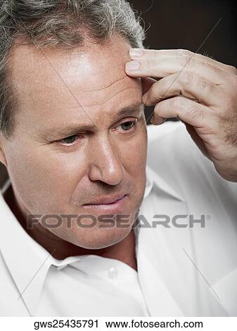 Close-up of a mature man touching his forehead View Large Photo Image Stock Image - Close-up of a mature man touching his forehead. Fotosearch