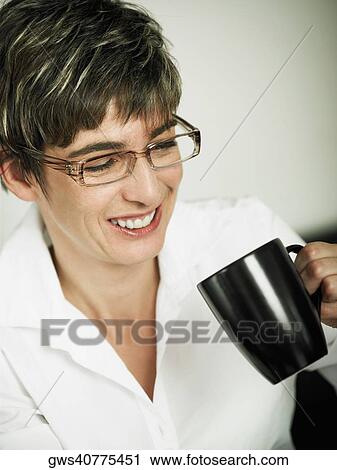 Close-up of a mature woman holding a cup of coffee and smiling View Large Photo Image Stock Image - Close-up of a mature woman holding a cup of coffee and smiling. Fotosearch