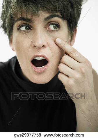 Close-up of a mature woman pointing towards her eye View Large Photo Image Stock Photo - Close-up of a mature woman pointing towards her eye. Fotosearch