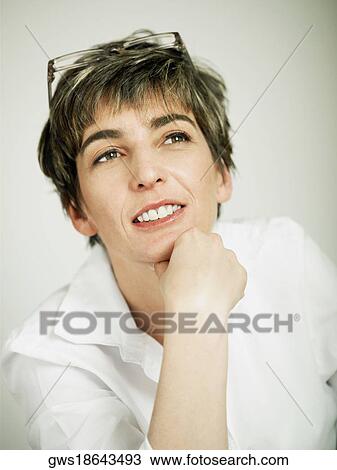 Stock Image - Close-up of a mature woman smiling with her hand on her chin. Fotosearch