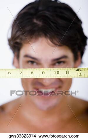 Close-up of a measuring tape in front of a mid adult man View Large Photo Image Picture - Close-up of a measuring tape in front of a mid adult man. Fotosearch