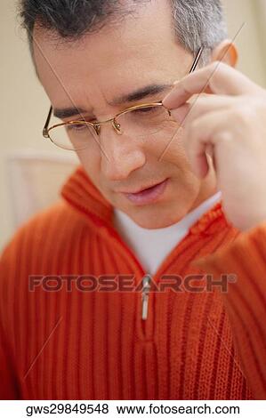 Close-up of a mid adult man adjusting his eyeglasses View Large Photo Image Stock Photo - Close-up of a mid adult man adjusting his eyeglasses. Fotosearch