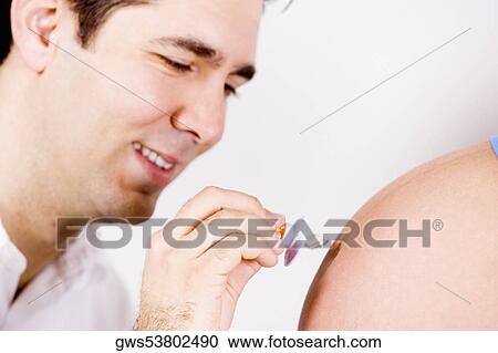 Close-up of a mid adult man holding a pacifier and touching it to a pregnant woman's abdomen View Large Photo Image Stock Image - Close-up of a mid adult man holding a pacifier and touching it to a pregnant woman's abdomen. Fotosearch