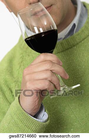 Stock Image - Close-up of a mid adult man holding a glass of wine. Fotosearch