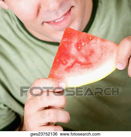 Stock Photograph - Close-up of a mid adult man holding a slice of watermelon. Fotosearch