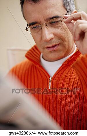 Picture - Close-up of a mid adult man holding his eyeglasses. Fotosearch