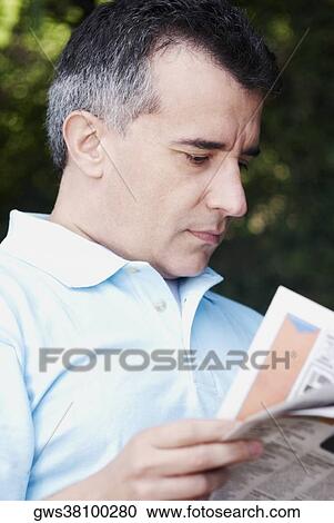 Stock Image - Close-up of a mid adult man reading a newspaper. Fotosearch