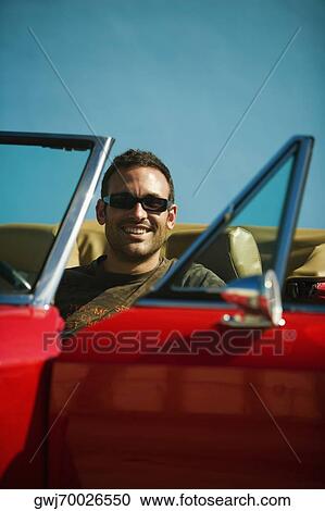 Stock Image - Close-up of a mid adult man sitting in a convertible car, Miami, Florida, USA. Fotosearch