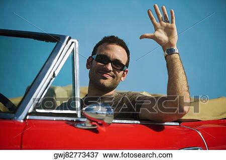 Close-up of a mid adult man sitting in a convertible car waving his hand, Miami, Florida, USA View Large Photo Image Stock Photo - Close-up of a mid adult man sitting in a convertible car waving his hand, Miami, Florida, USA. Fotosearch