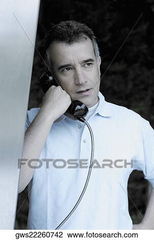 Close-up of a mid adult man talking on a pay phone View Large Photo Image Stock Image - Close-up of a mid adult man talking on a pay phone. Fotosearch