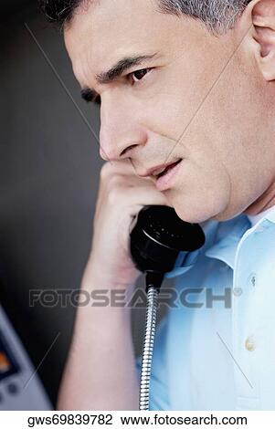 Close-up of a mid adult man talking on a pay phone View Large Photo Image Stock Image - Close-up of a mid adult man talking on a pay phone. Fotosearch