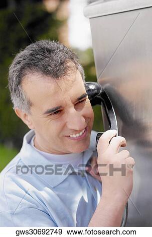 Close-up of a mid adult man talking on a pay phone View Large Photo Image Stock Photo - Close-up of a mid adult man talking on a pay phone. Fotosearch