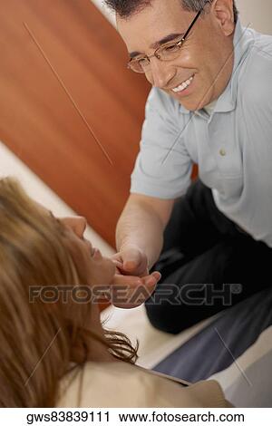 Stock Image - Close-up of a mid adult man touching the chin of a mid adult woman. Fotosearch