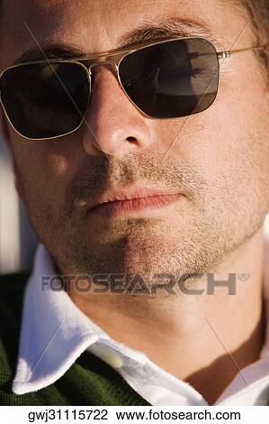 Close-up of a mid adult man wearing sunglasses View Large Photo Image Stock Image - Close-up of a mid adult man wearing sunglasses. Fotosearch