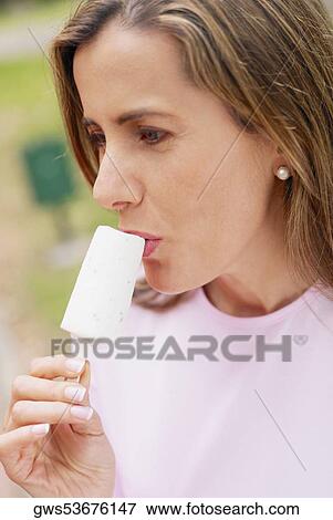 Close-up of a mid adult woman eating an ice-cream View Large Photo Image Stock Photo - Close-up of a mid adult woman eating an ice-cream. Fotosearch